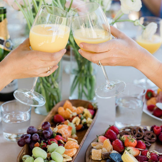 two glasses of orange juice doing "cheers"