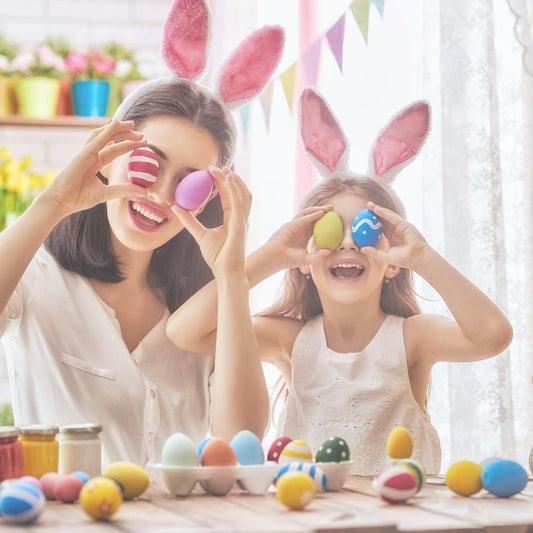 a mother and daughter holing easter eggs up to their eyes