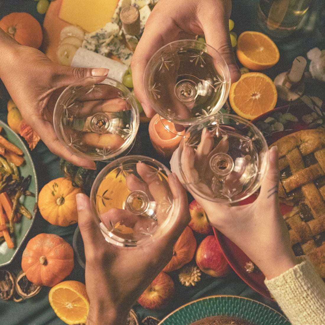 four glasses "cheers"-ing in the center of a thanksgiving table