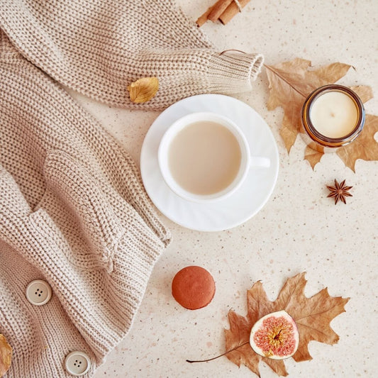 a cozy sweater and a cup of coffee surrounded by leaves