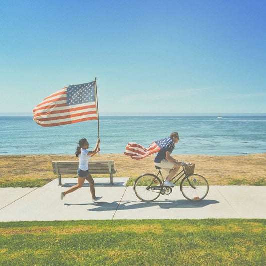 a man riding a bike and a women running behind him with an American flag