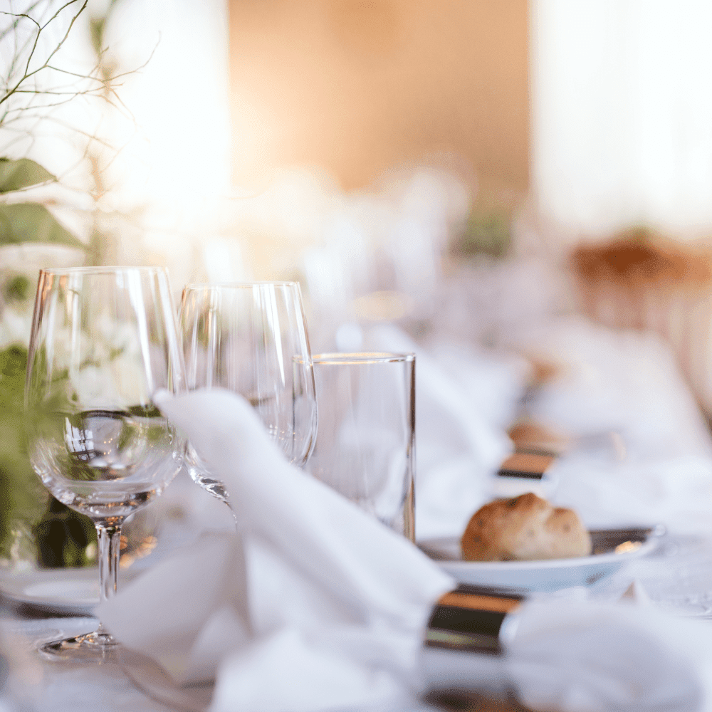 photo of a table setting with napkins, glasses and white linens