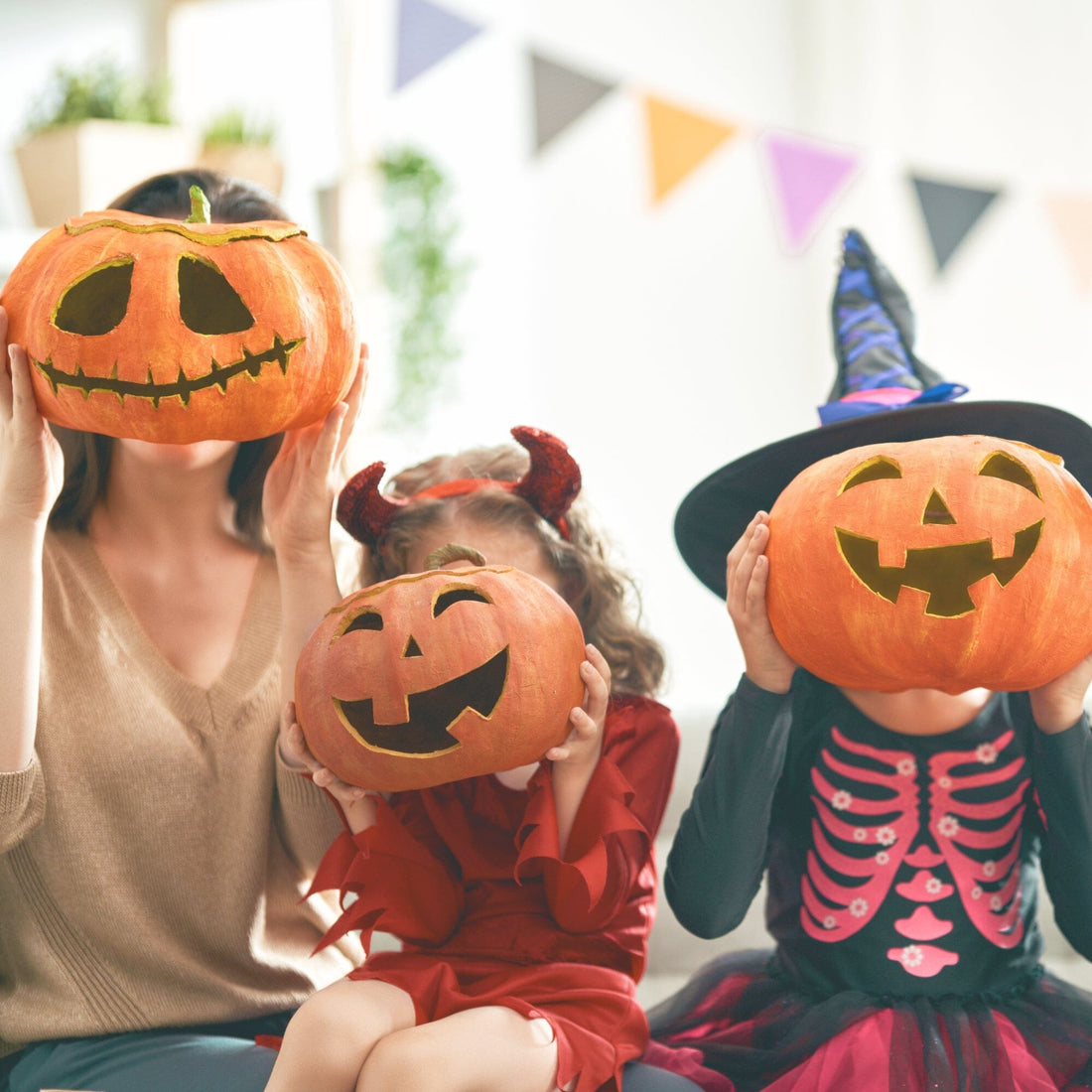 photo of 3 people holding jack-o-lanterns in front of their faces